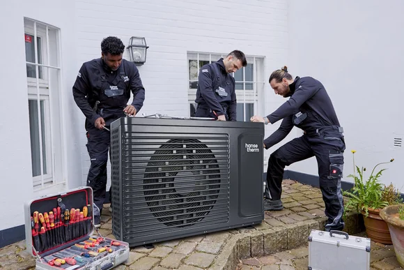 Drei Personen montieren eine Wärmepumpe.
